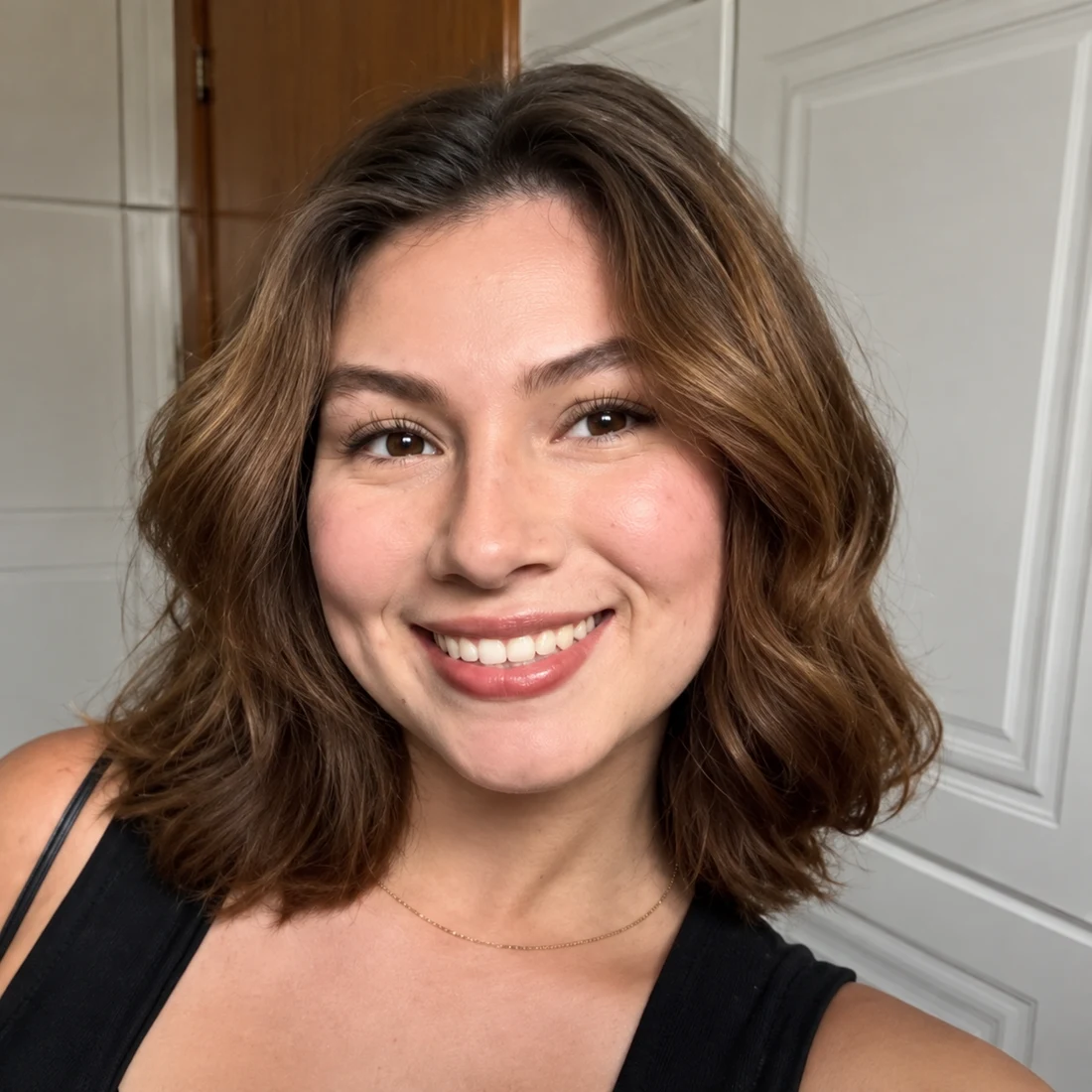Millena Palinkas sorrindo, com cabelo solto e blusa preta.